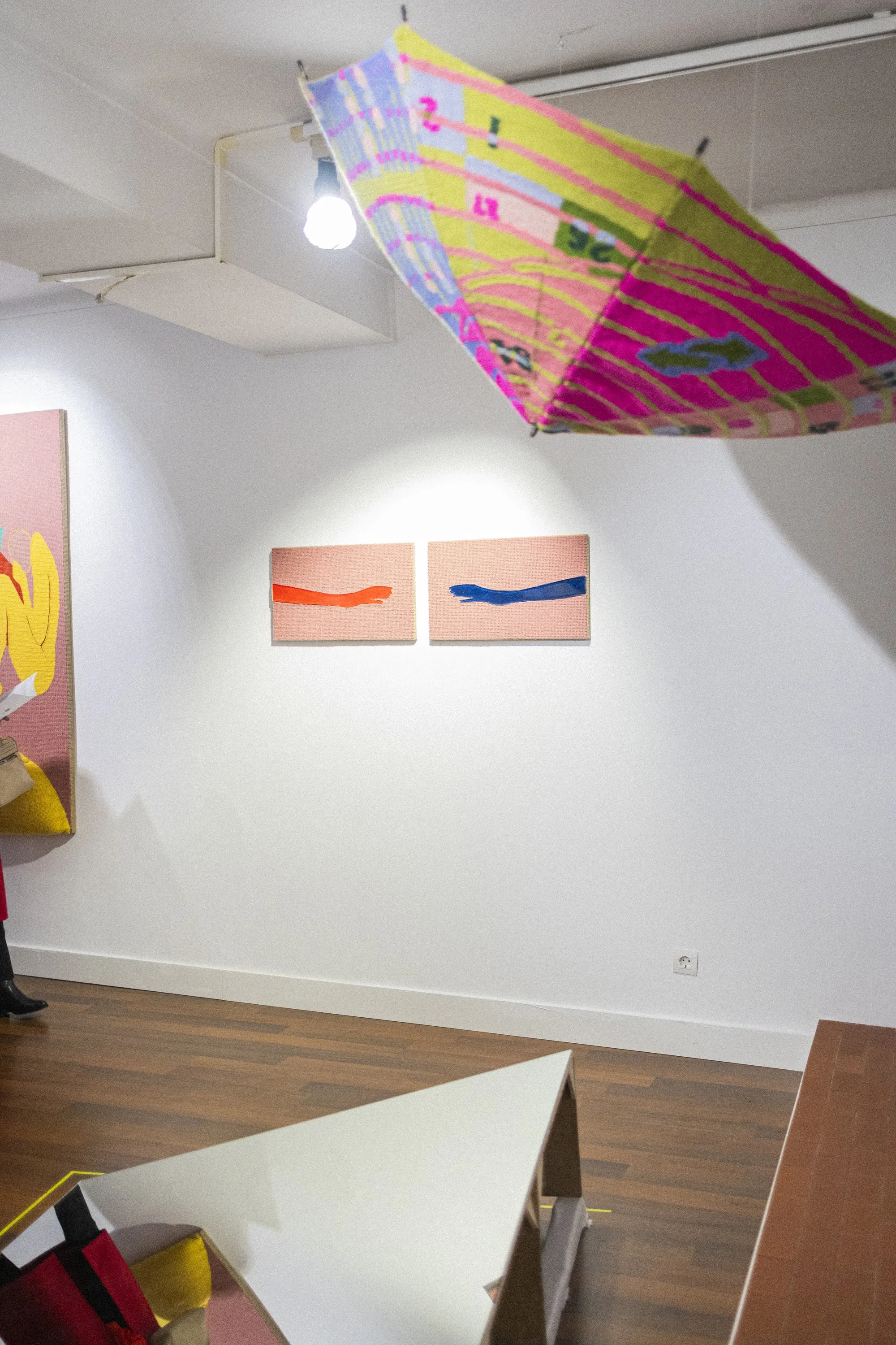 Installation view of ÁGORA with a suspended textile work