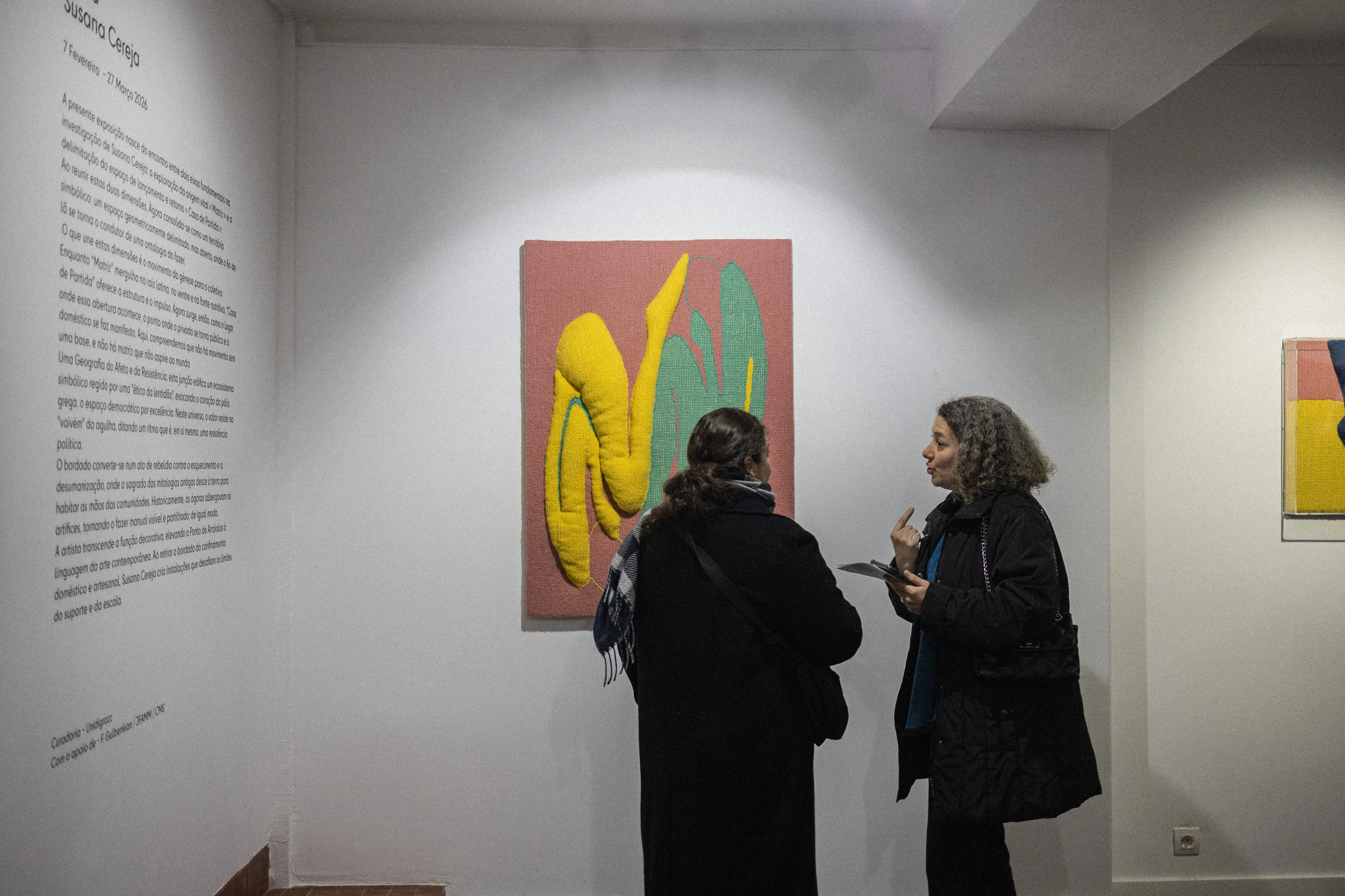 Visitors viewing ÁGORA beside the exhibition wall text