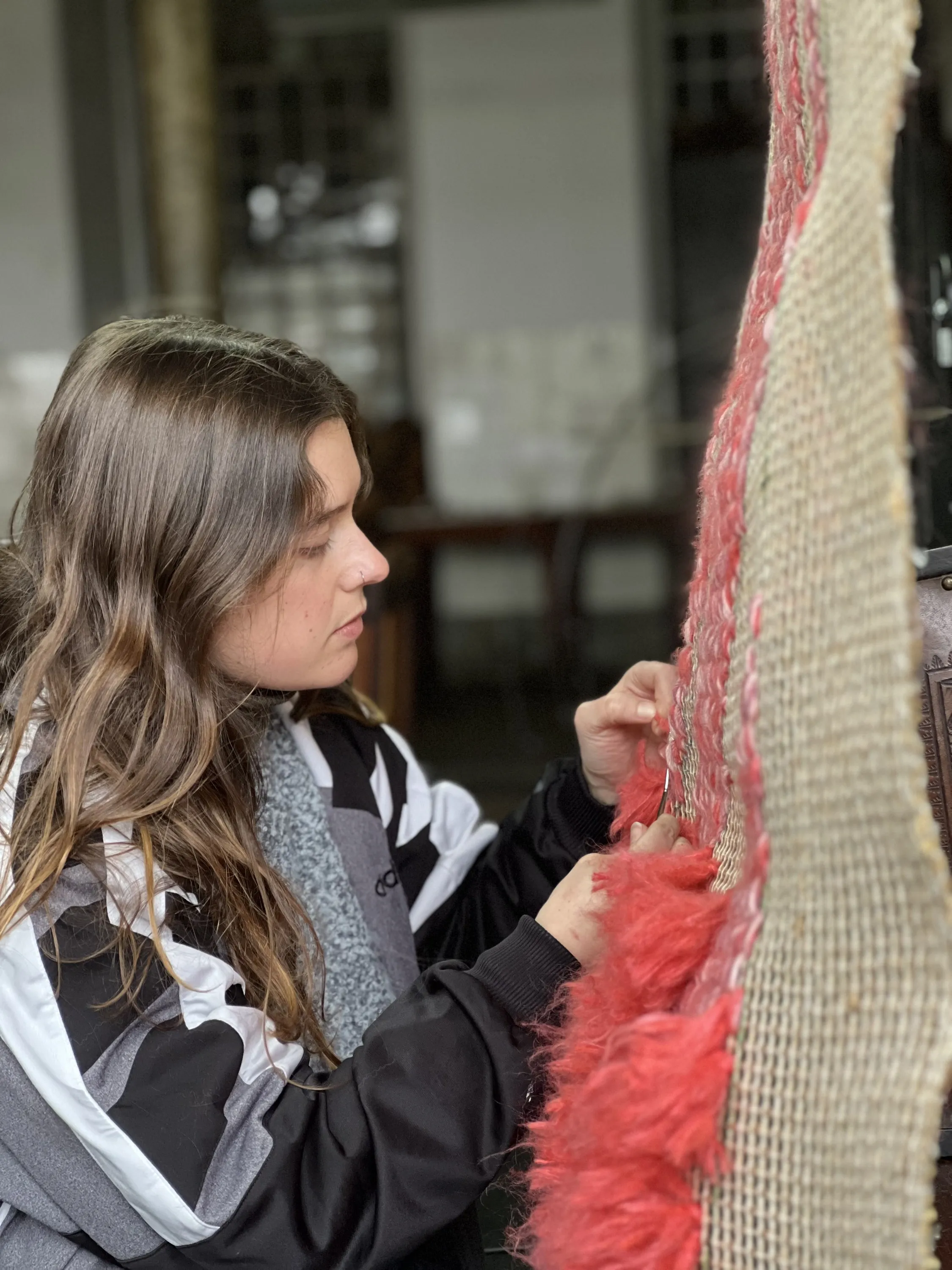 Textile stitching in progress on a large burlap panel during TEIAS CRIATIVAS.