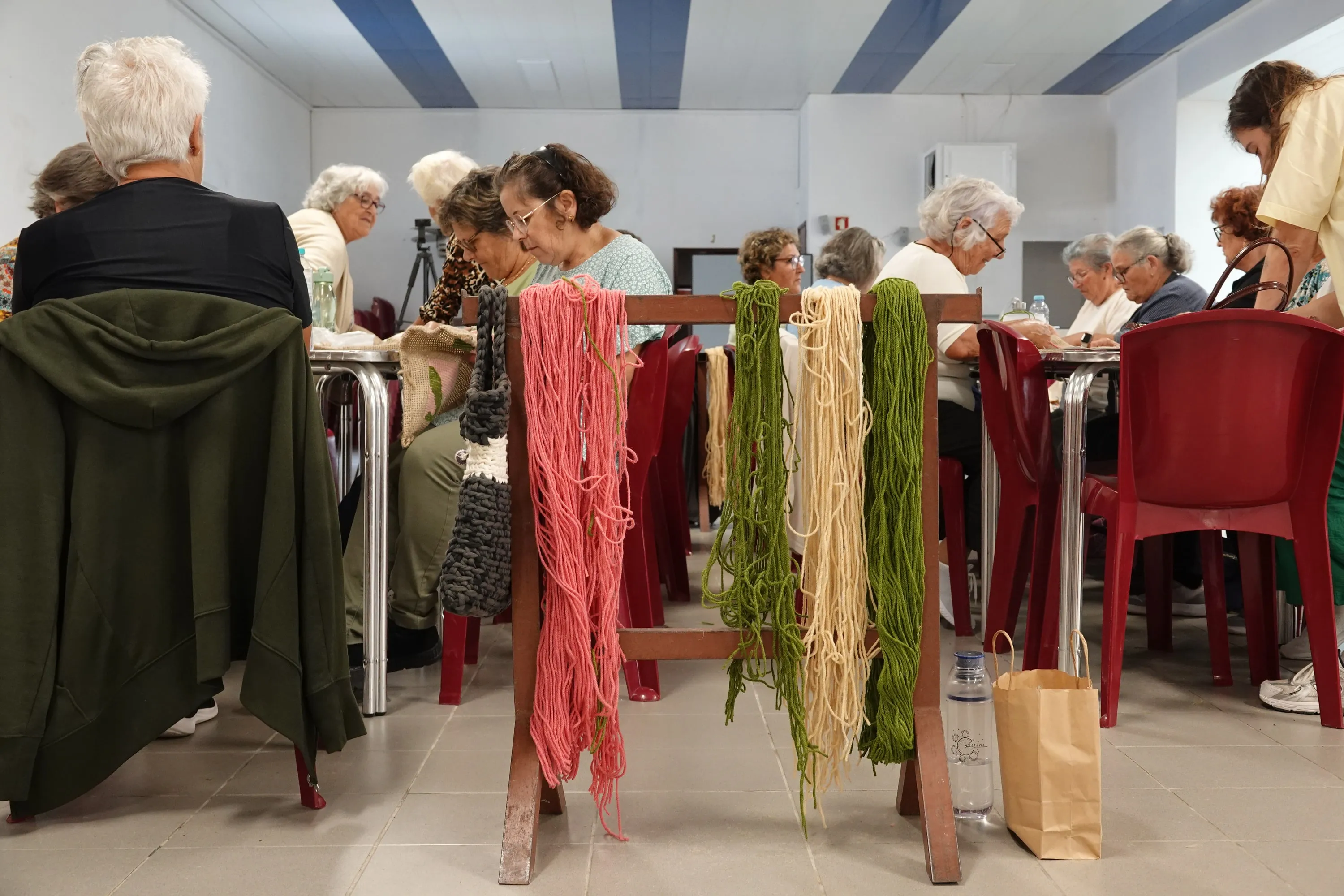 Workshop view with bundles of coloured wool in the foreground and participants working behind.