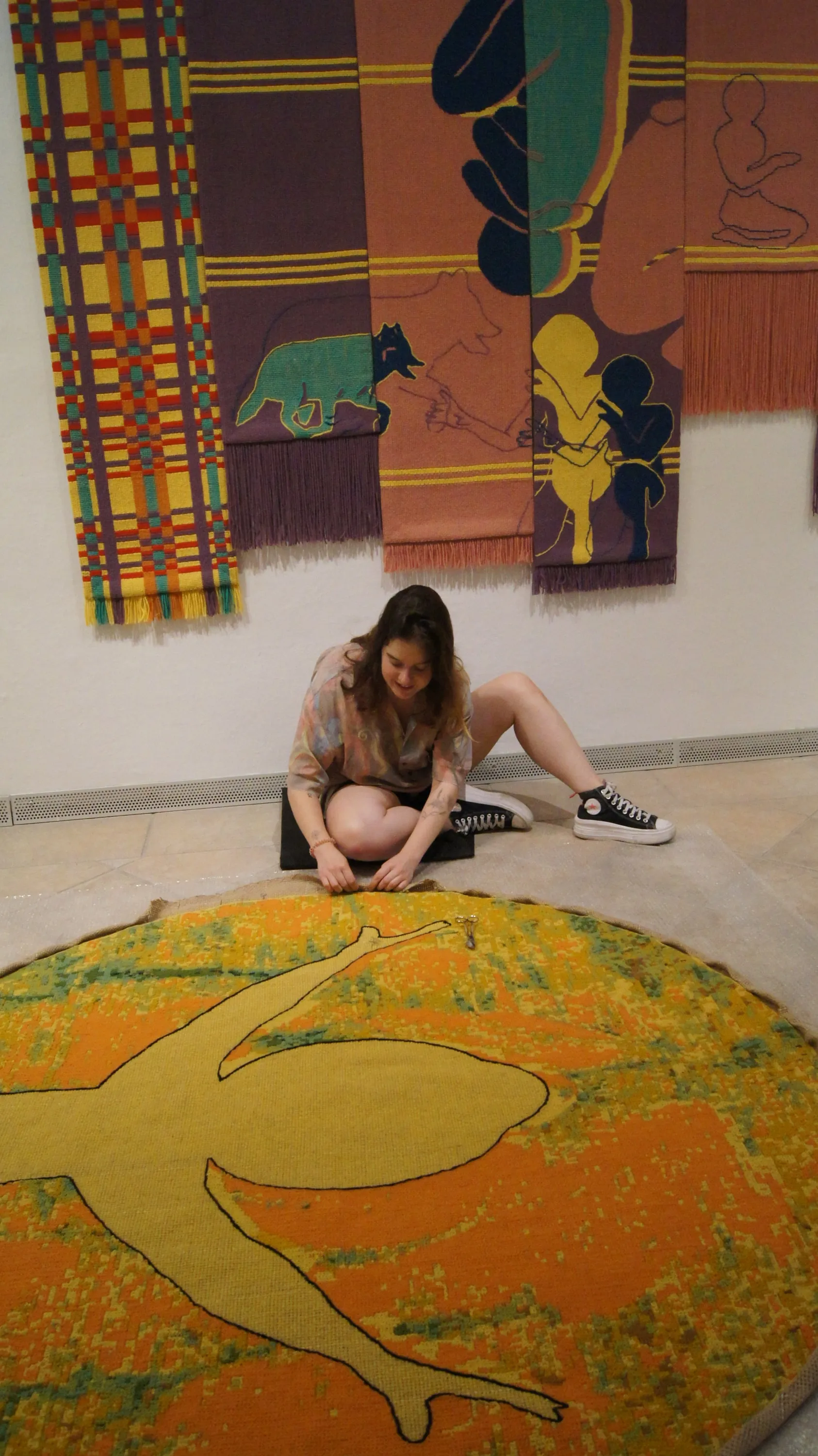 HELIA being worked on inside the gallery space, with another tapestry displayed behind it.