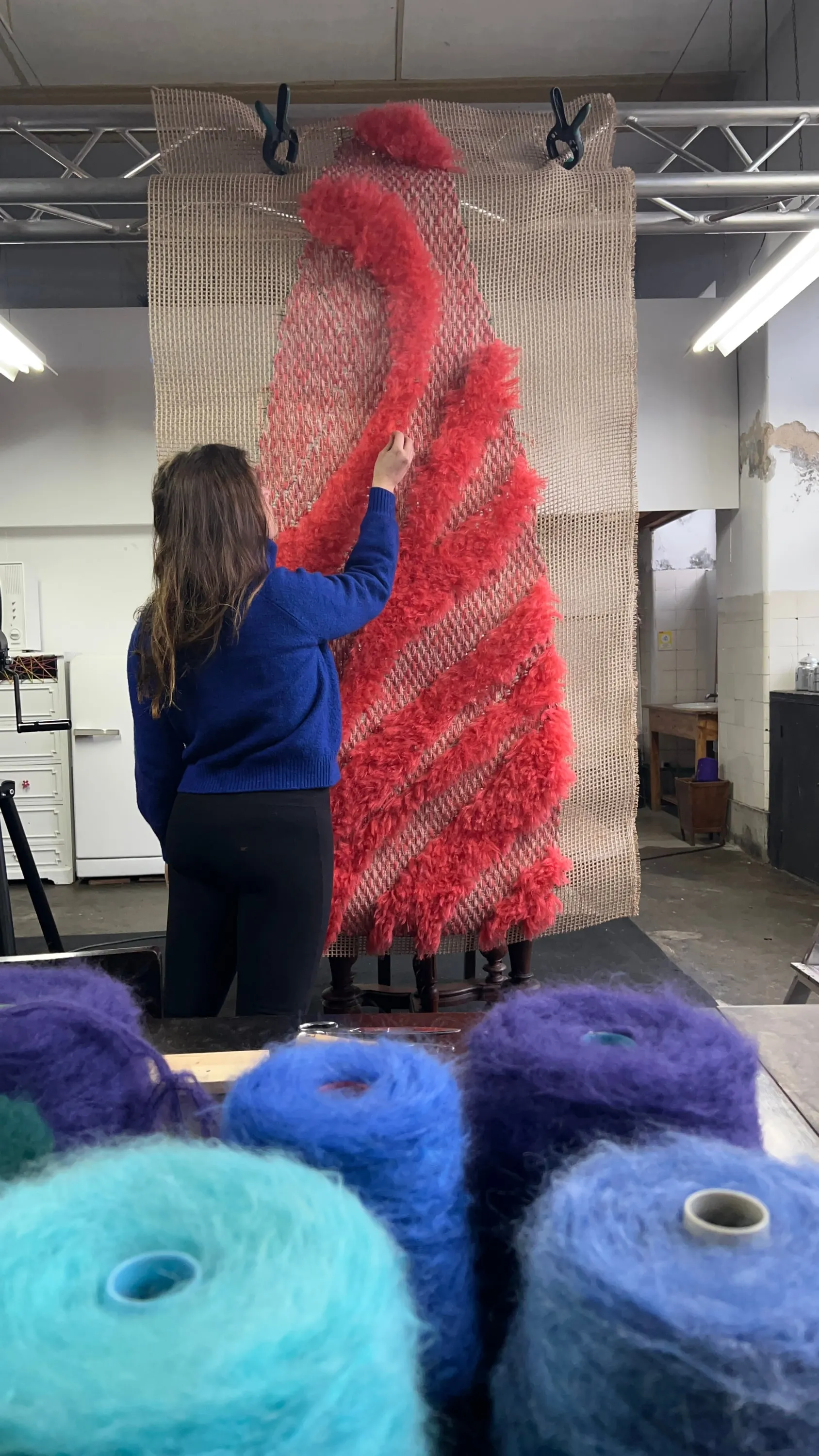 Large textile panel in progress with raised red fibre elements.