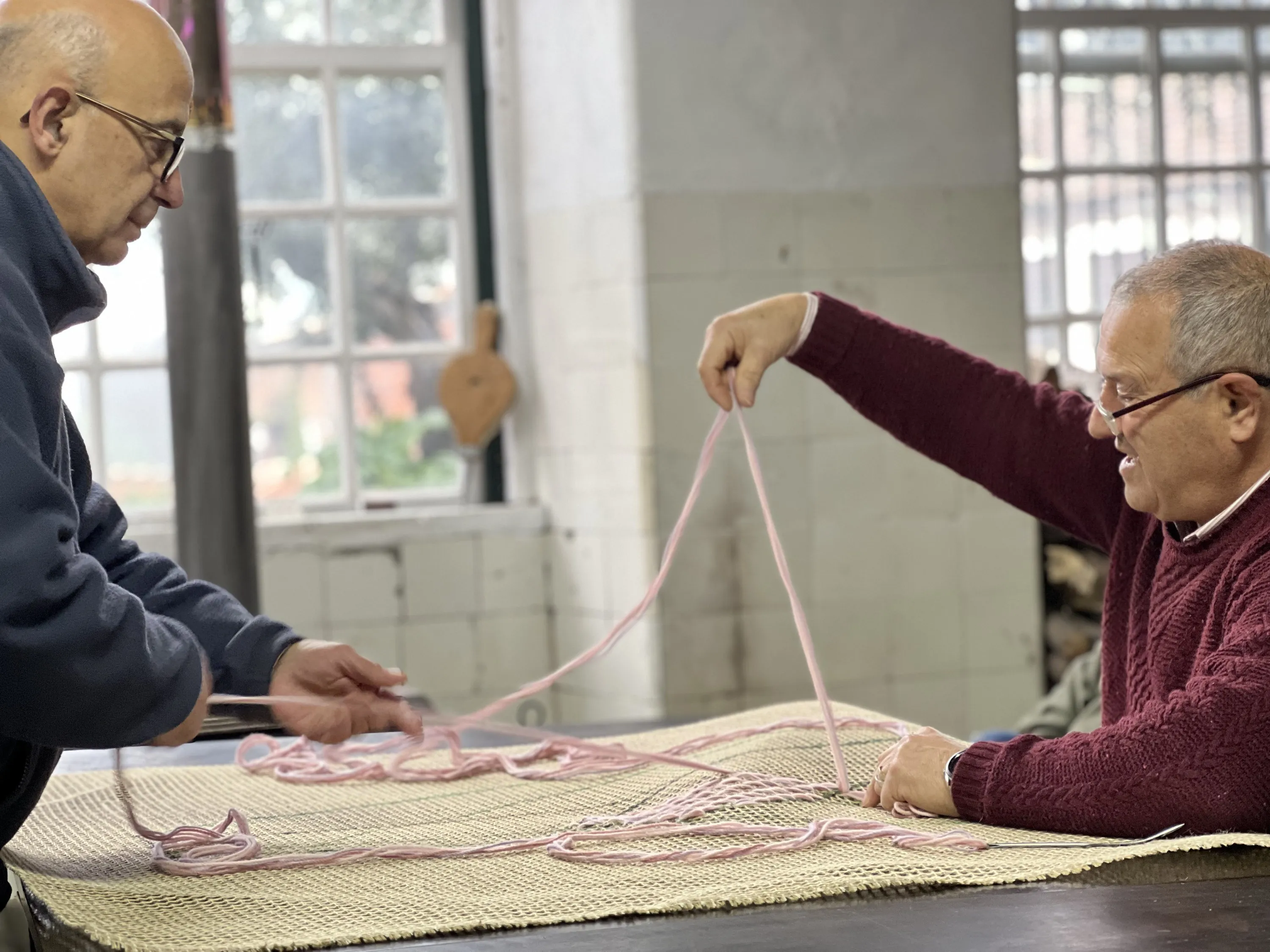 Two participants working together with yarn on a large textile panel.