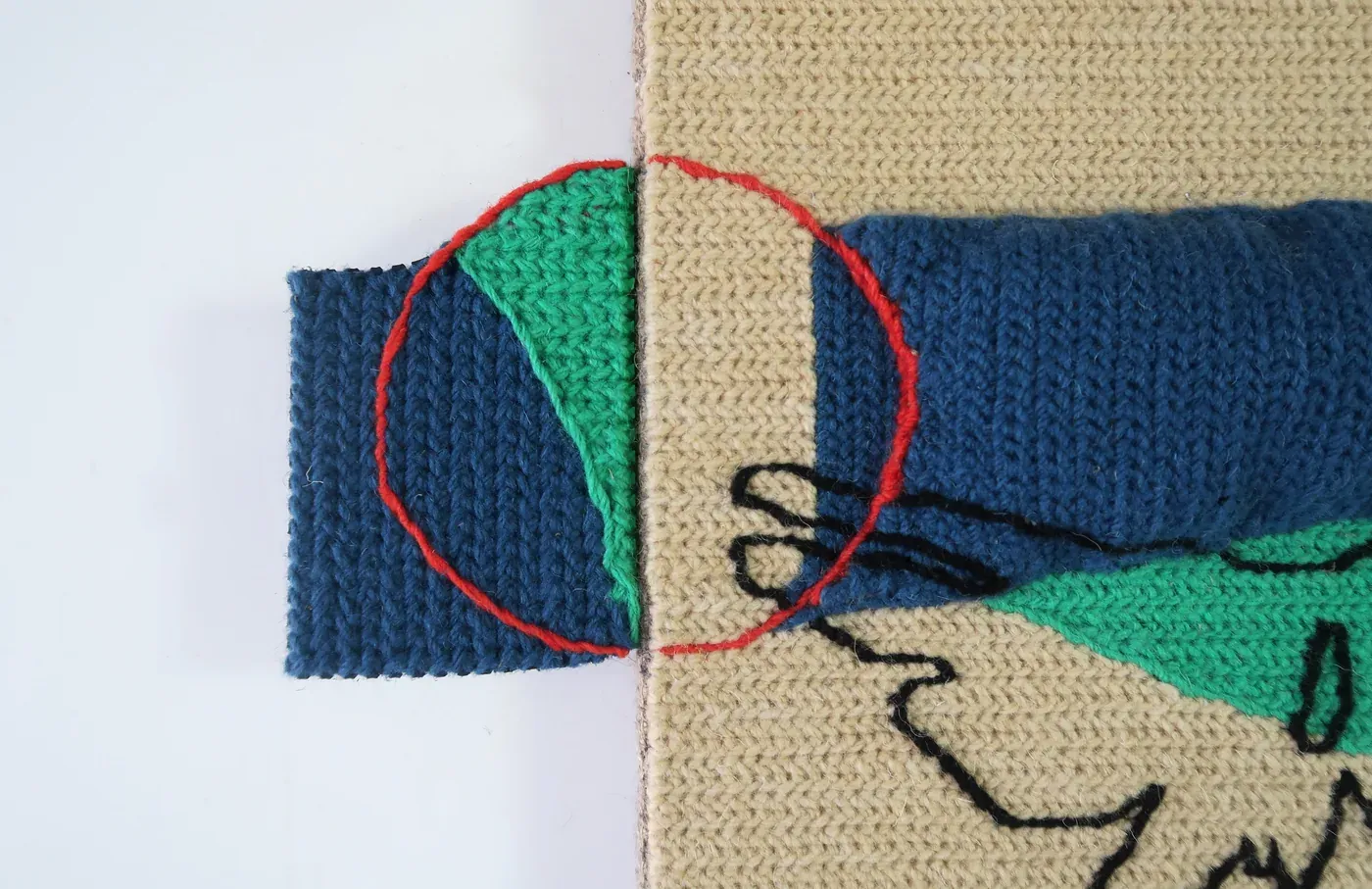 Detalhe de MIND GAME #2, mostrando o contorno circular vermelho sobre planos têxteis verdes, azul-escuros e de serapilheira.